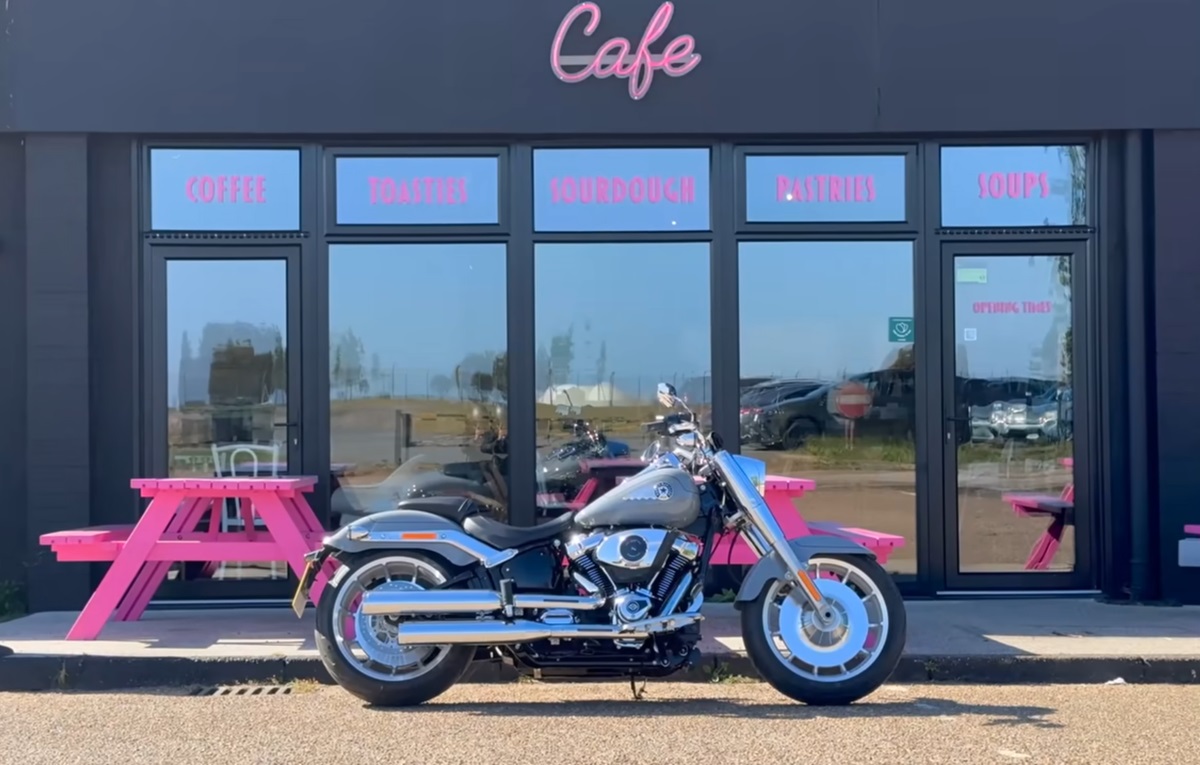 A Harley-Davidson Fat Boy in a video review parked by a cafe